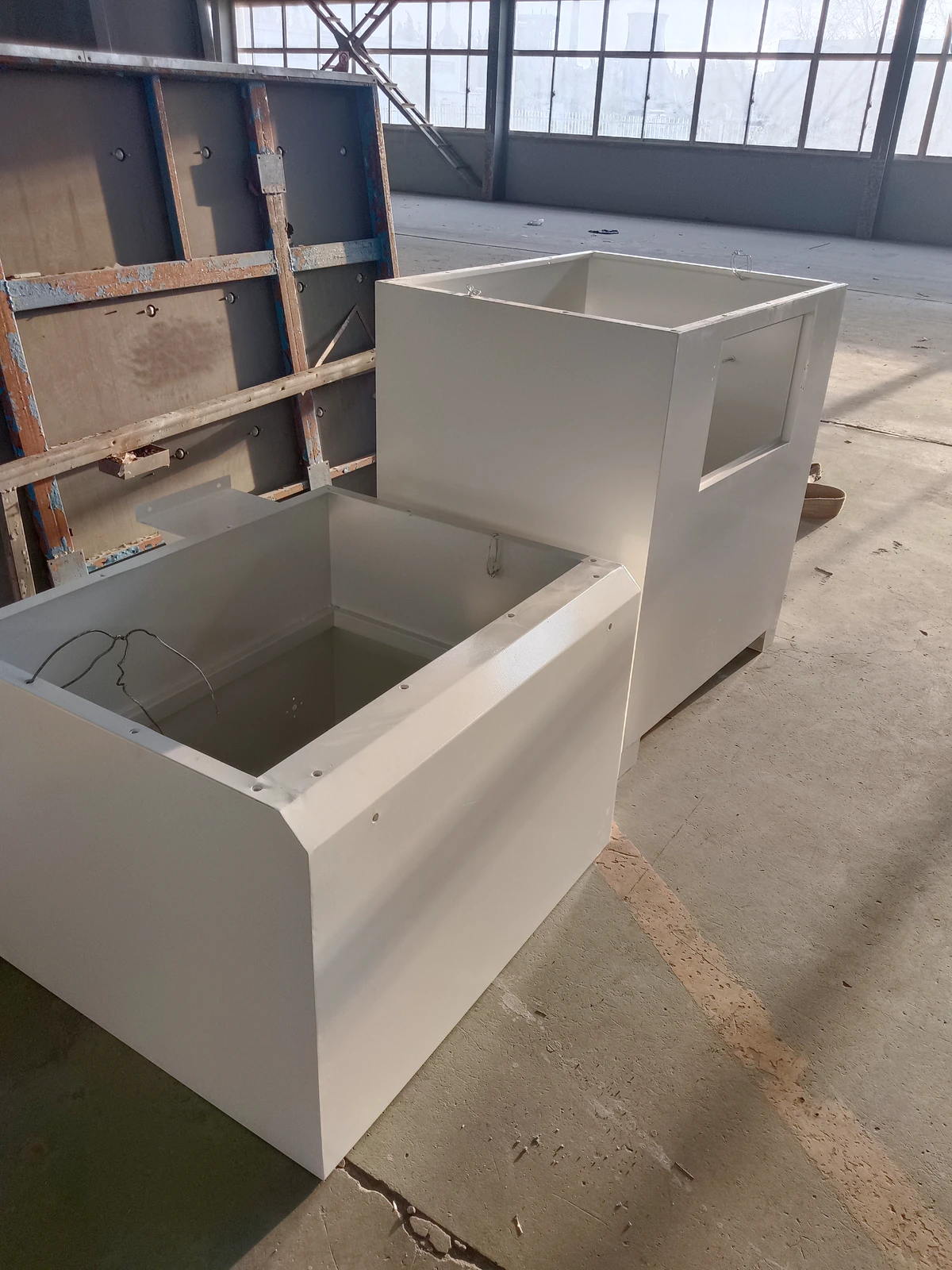 Two painted metal enclosures showing open tops, mounting holes and surface details